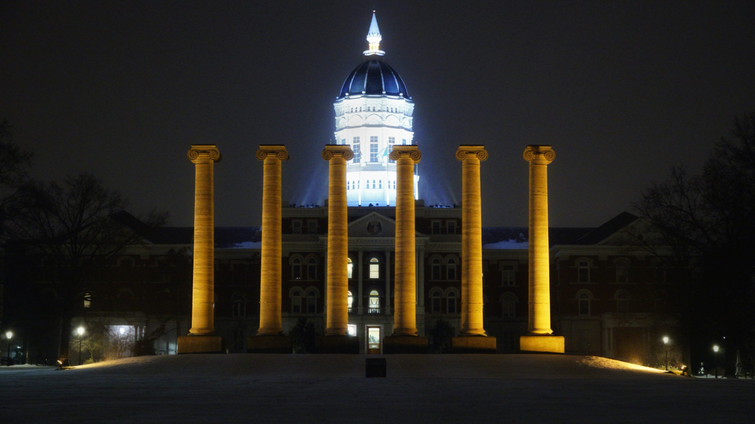 The Columns and Jesse Hall at the University of Missouri, lit gold against a night sky